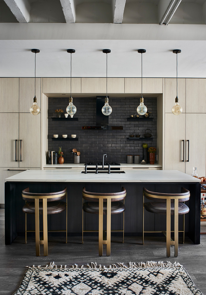 Trendy galley medium tone wood floor and gray floor kitchen photo in Atlanta with an undermount sink, flat-panel cabinets, light wood cabinets, black backsplash, paneled appliances, an island and white countertops