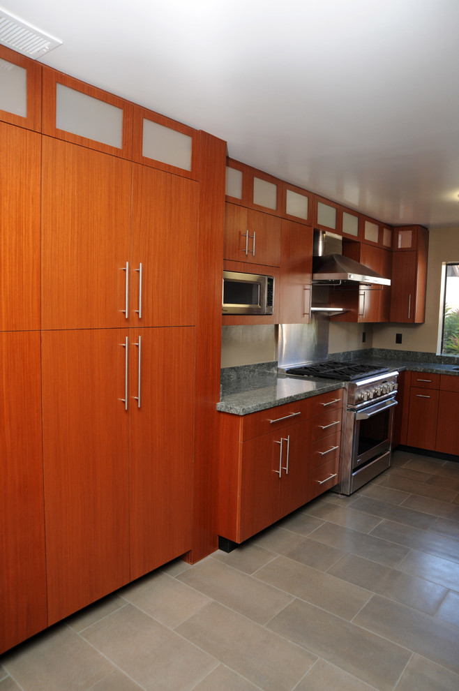Bild på ett avskilt, litet funkis u-kök, med en undermonterad diskho, släta luckor, skåp i mellenmörkt trä, granitbänkskiva, rostfria vitvaror, vinylgolv och beiget golv