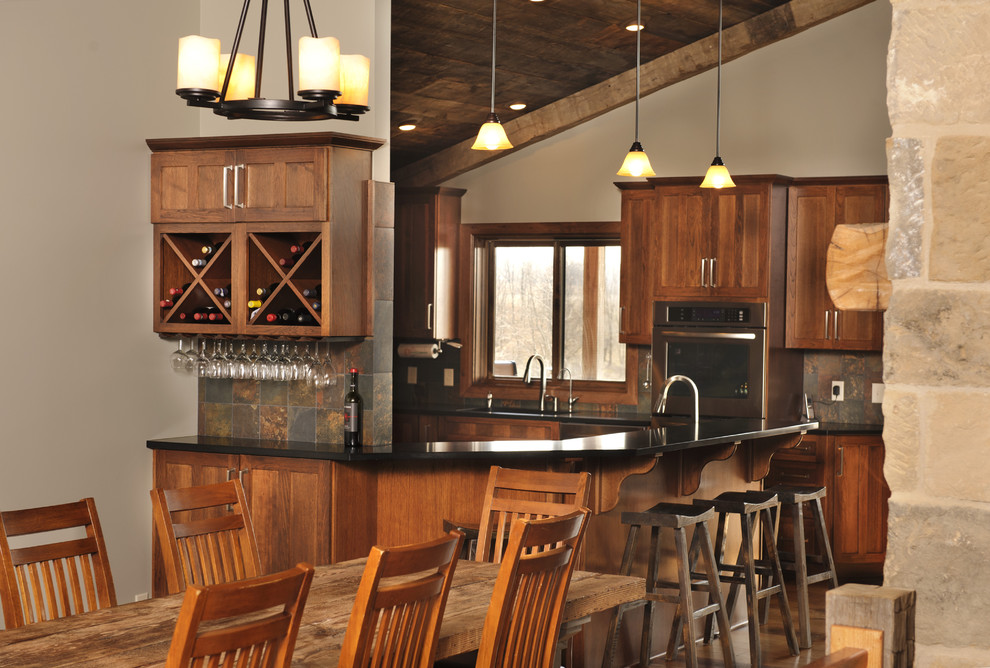 Urige Küche mit hellbraunen Holzschränken, bunter Rückwand, Küchengeräten aus Edelstahl, Rückwand aus Schiefer und Mauersteinen in Cleveland