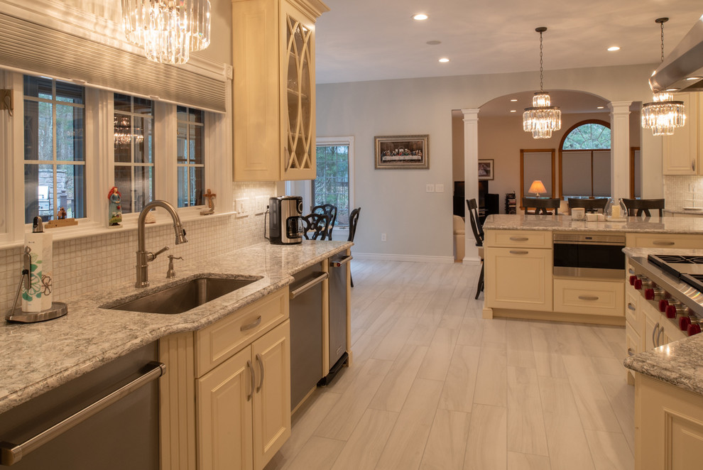 This is an example of an expansive traditional kitchen/diner in Boston with a submerged sink, raised-panel cabinets, white cabinets, engineered stone countertops, white splashback, mosaic tiled splashback, stainless steel appliances, porcelain flooring, multiple islands, grey floors and beige worktops.