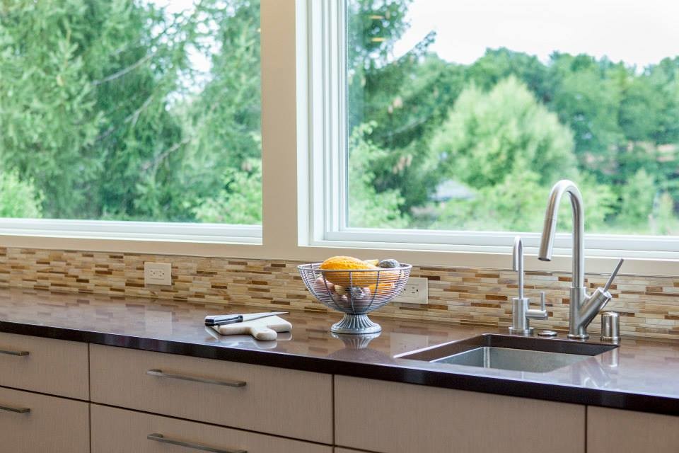 Esempio di una cucina abitabile moderna con lavello a vasca singola, ante in legno chiaro, top in quarzo composito, paraspruzzi multicolore, paraspruzzi con piastrelle di vetro e elettrodomestici in acciaio inossidabile