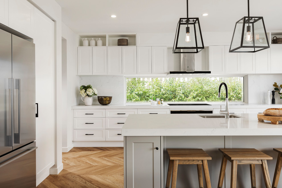Inspiration for a large modern galley light wood floor and brown floor eat-in kitchen remodel in Melbourne with an undermount sink, shaker cabinets, white cabinets, quartz countertops, white backsplash, stone slab backsplash, black appliances, an island and white countertops