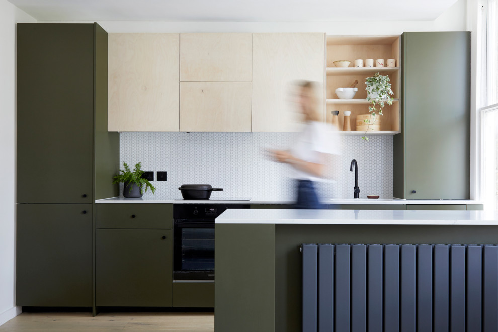 Medium sized contemporary galley open plan kitchen in London with quartz worktops, white splashback, an island, white worktops, a submerged sink, flat-panel cabinets, green cabinets, integrated appliances and beige floors.