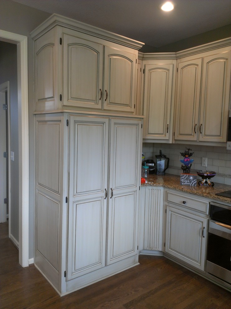 Foto de cocina clásica con armarios con paneles con relieve, encimera de granito, electrodomésticos de acero inoxidable y suelo de madera en tonos medios