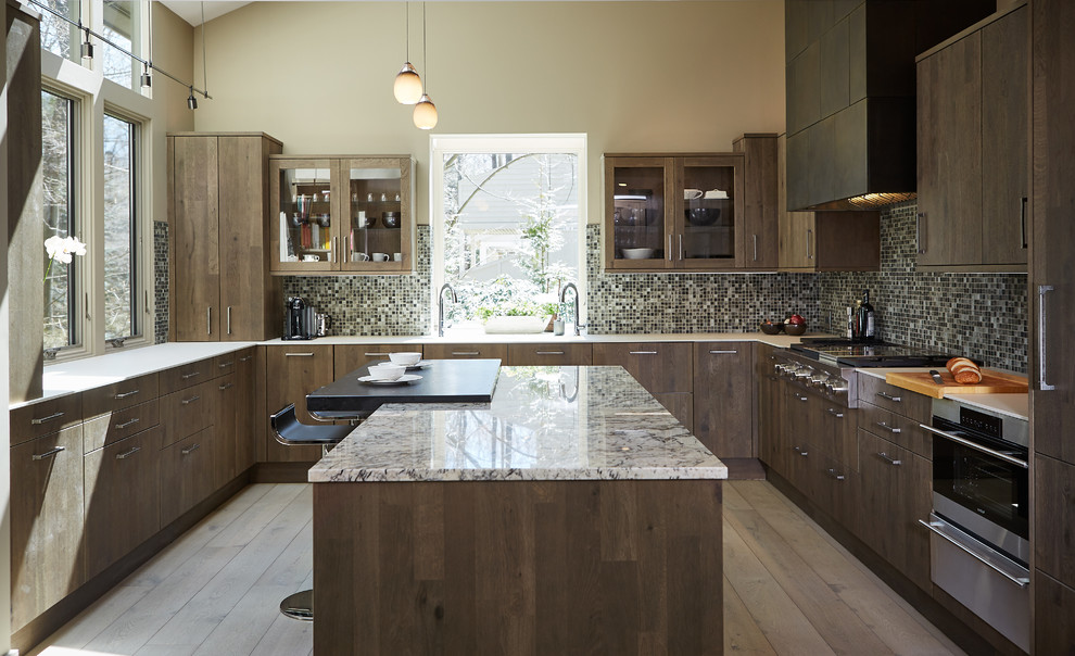 Inspiration for a large contemporary u-shaped kitchen in Detroit with a submerged sink, shaker cabinets, dark wood cabinets, granite worktops, metallic splashback, glass tiled splashback, stainless steel appliances, an island, medium hardwood flooring and brown floors.