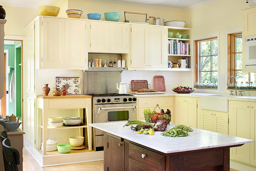 Immagine di una cucina classica con elettrodomestici in acciaio inossidabile, lavello stile country e ante gialle