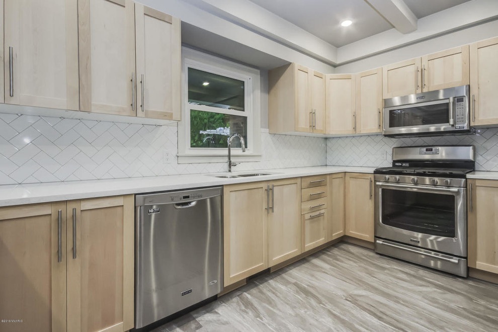 Foto di una cucina tradizionale di medie dimensioni con lavello sottopiano, ante in stile shaker, ante in legno chiaro, top in quarzo composito, paraspruzzi bianco, paraspruzzi con piastrelle in ceramica, elettrodomestici in acciaio inossidabile, pavimento in vinile e penisola