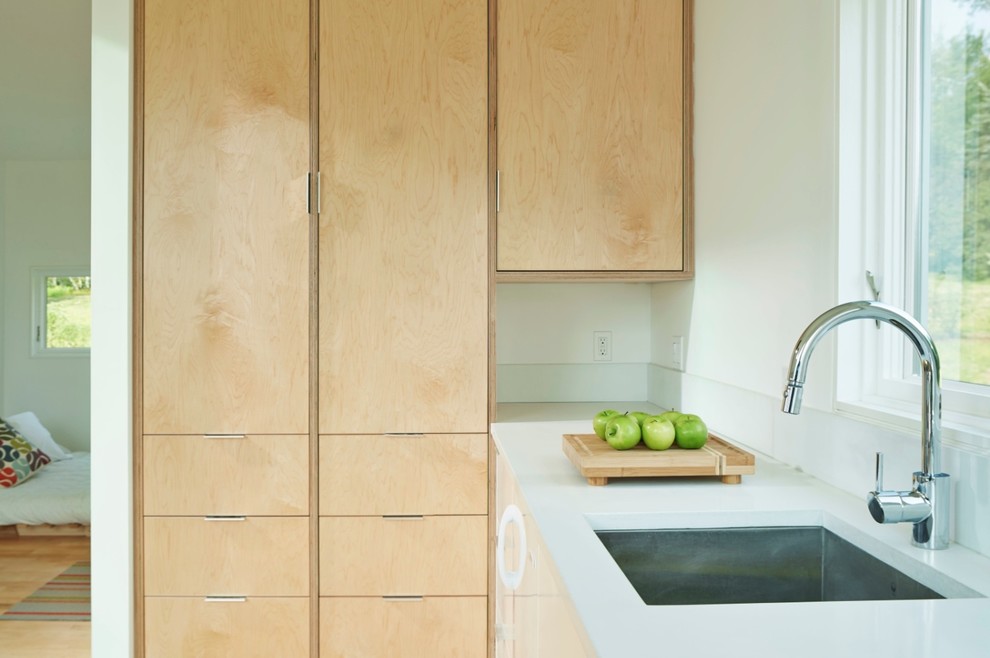 Exempel på ett litet modernt kök, med en undermonterad diskho, släta luckor, vita skåp, bänkskiva i betong, vitt stänkskydd, vita vitvaror och ljust trägolv