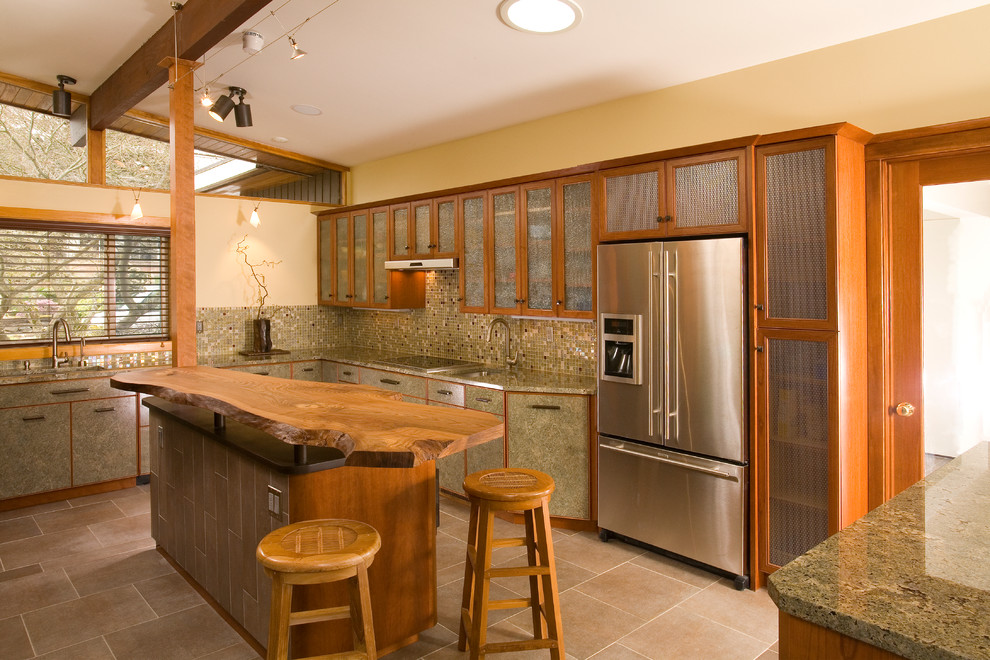 This is an example of a large world-inspired u-shaped kitchen/diner in Seattle with mosaic tiled splashback, stainless steel appliances, an island, a submerged sink, glass-front cabinets, medium wood cabinets, granite worktops, multi-coloured splashback, porcelain flooring and beige floors.