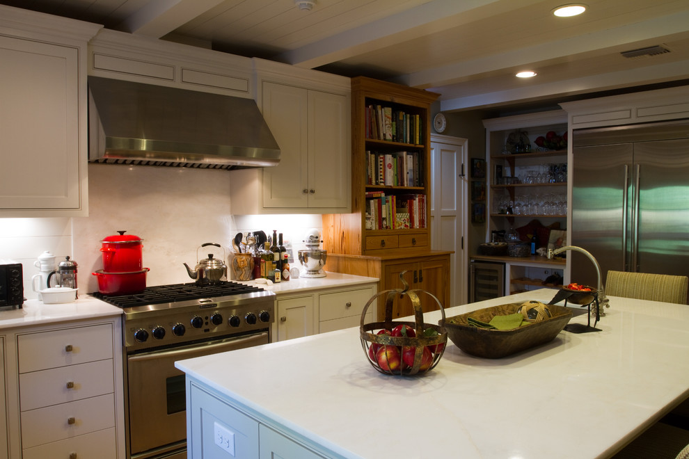 Geschlossene, Mittelgroße Mid-Century Küche in U-Form mit Unterbauwaschbecken, Schrankfronten im Shaker-Stil, Marmor-Arbeitsplatte, Küchenrückwand in Weiß, Küchengeräten aus Edelstahl, braunem Holzboden und Kücheninsel in New Orleans