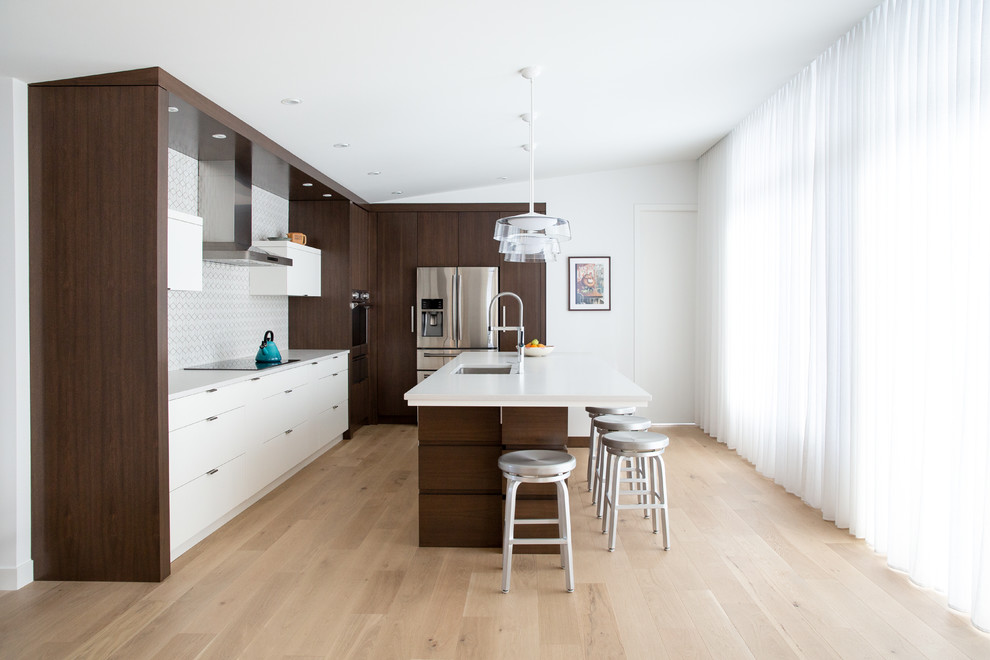 Mid-century modern light wood floor and beige floor kitchen photo in Calgary with an undermount sink, flat-panel cabinets, white cabinets, multicolored backsplash, stainless steel appliances, an island and white countertops