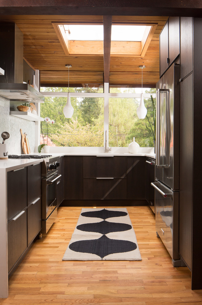 Small 1950s galley medium tone wood floor and yellow floor eat-in kitchen photo in Seattle with an undermount sink, flat-panel cabinets, dark wood cabinets, marble countertops, gray backsplash, mosaic tile backsplash, stainless steel appliances and no island