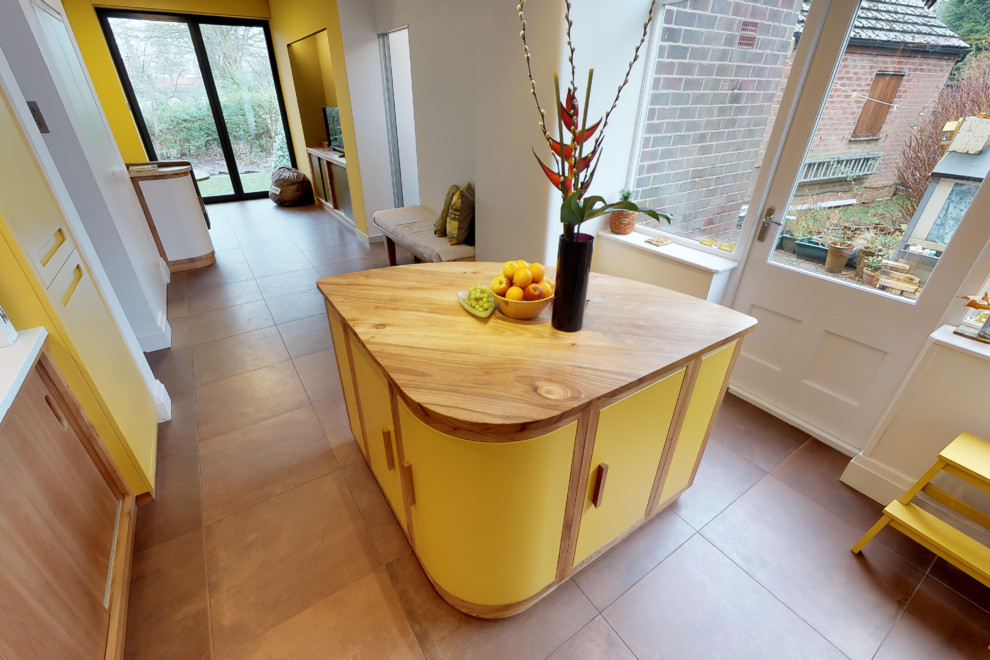 Große Mid-Century Küche in L-Form mit integriertem Waschbecken, flächenbündigen Schrankfronten, gelben Schränken, Küchenrückwand in Grau, Küchengeräten aus Edelstahl, Porzellan-Bodenfliesen, Kücheninsel, braunem Boden und Arbeitsplatte aus Holz in Manchester