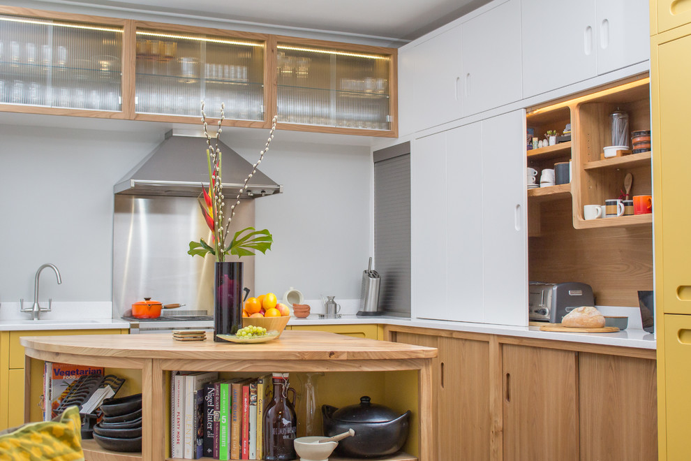 Foto på ett stort 50 tals l-kök, med en integrerad diskho, släta luckor, gula skåp, bänkskiva i kvarts, grått stänkskydd, rostfria vitvaror, klinkergolv i porslin, en köksö och brunt golv