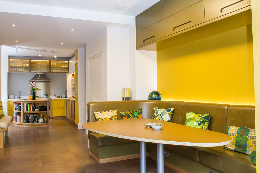 Große Retro Wohnküche in L-Form mit integriertem Waschbecken, flächenbündigen Schrankfronten, gelben Schränken, Quarzwerkstein-Arbeitsplatte, Küchengeräten aus Edelstahl, Porzellan-Bodenfliesen, Kücheninsel und braunem Boden in Manchester