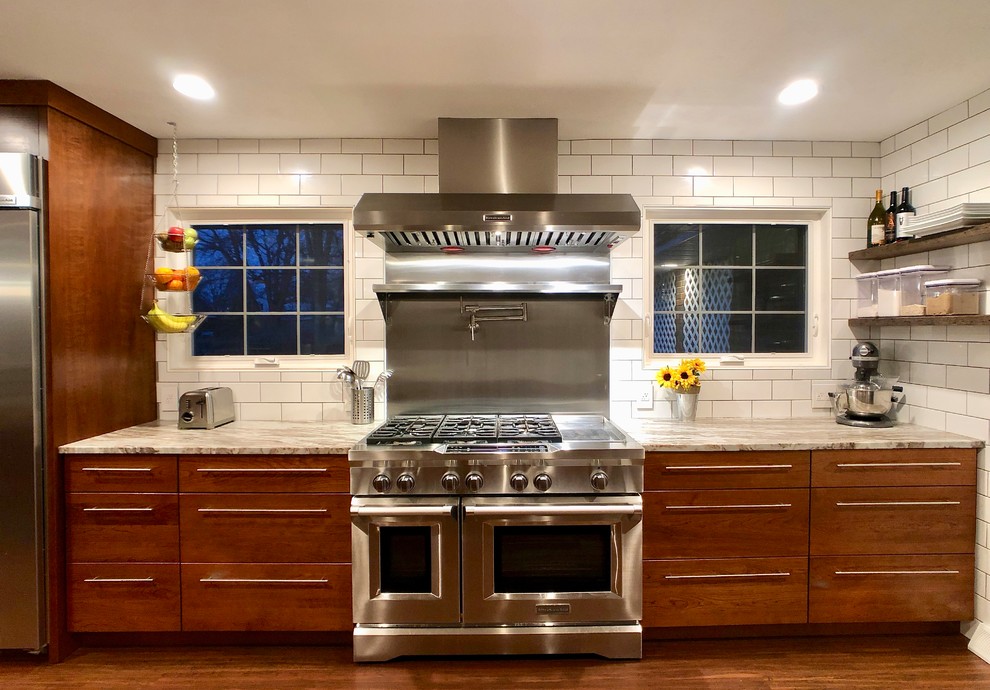 オースティンにある高級な中くらいなモダンスタイルのおしゃれなキッチン (シングルシンク、フラットパネル扉のキャビネット、中間色木目調キャビネット、大理石カウンター、白いキッチンパネル、サブウェイタイルのキッチンパネル、シルバーの調理設備、クッションフロア、茶色い床、グレーのキッチンカウンター) の写真