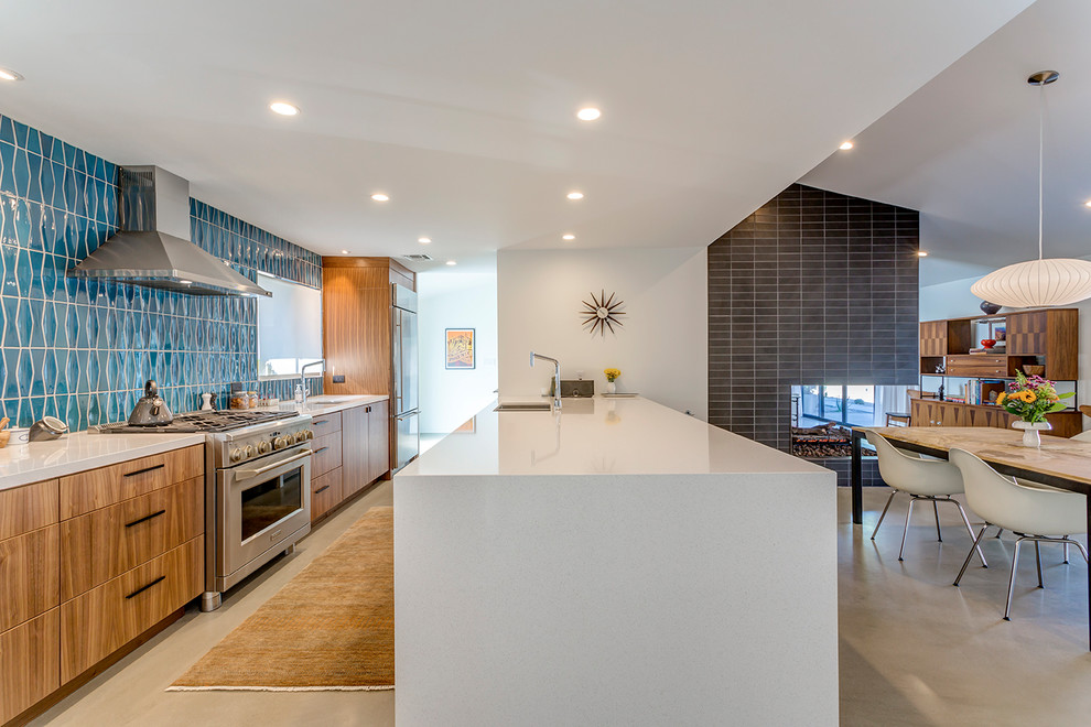 Example of a mid-century modern galley concrete floor and gray floor eat-in kitchen design in Phoenix with an undermount sink, flat-panel cabinets, medium tone wood cabinets, quartz countertops, blue backsplash, ceramic backsplash, stainless steel appliances and a peninsula