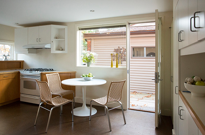 На фото: прямая кухня среднего размера в стиле ретро с обеденным столом, плоскими фасадами, светлыми деревянными фасадами и пробковым полом