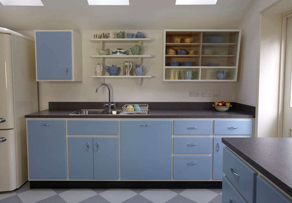 Photo of a medium sized midcentury l-shaped kitchen/diner in London with a double-bowl sink, flat-panel cabinets, laminate countertops, grey splashback, integrated appliances, lino flooring, no island, multi-coloured floors and grey worktops.