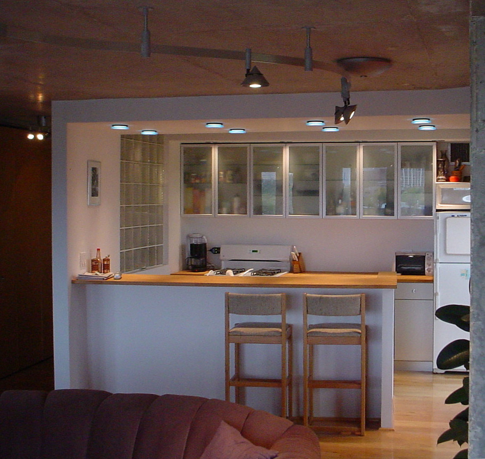 Idéer för små funkis kök, med en dubbel diskho, luckor med glaspanel, skåp i rostfritt stål, träbänkskiva, vita vitvaror, ljust trägolv och en halv köksö