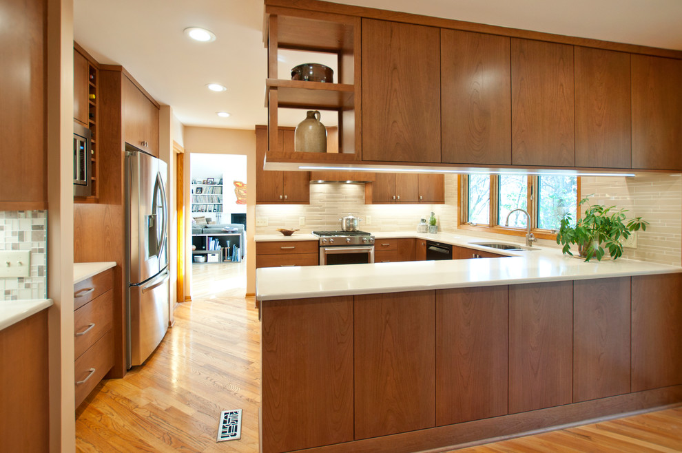 This is an example of a medium sized retro u-shaped kitchen/diner in Nashville with a submerged sink, flat-panel cabinets, medium wood cabinets, engineered stone countertops, beige splashback, mosaic tiled splashback, stainless steel appliances, a breakfast bar, light hardwood flooring, brown floors and beige worktops.