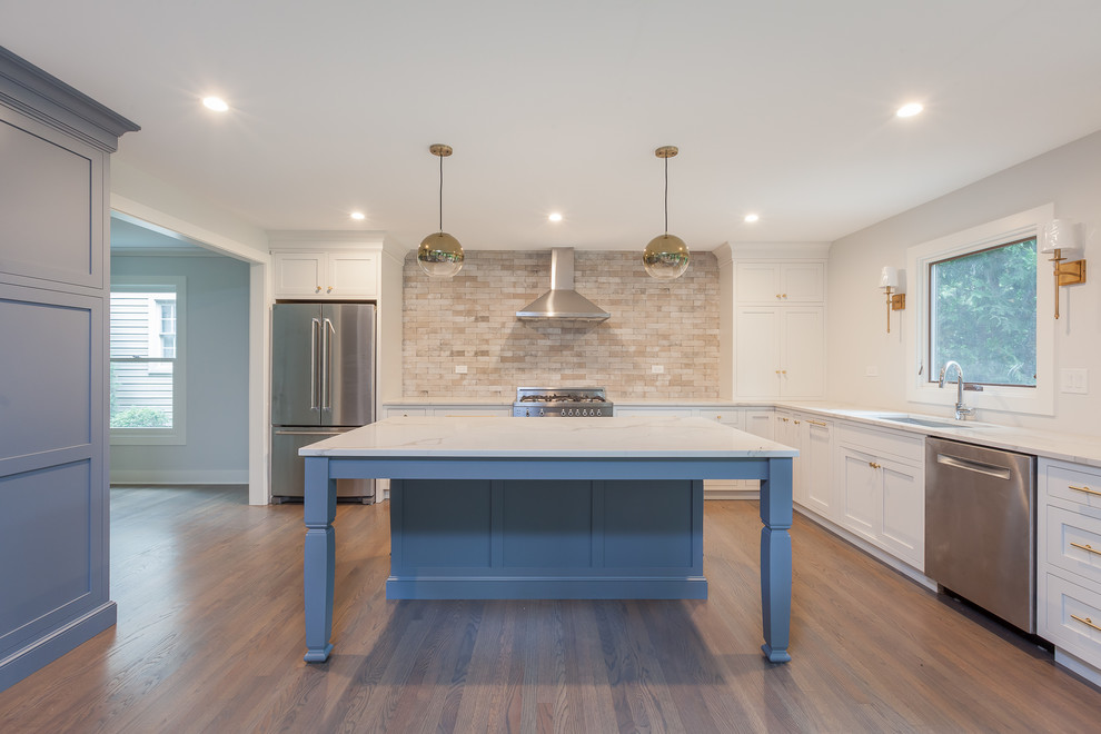 Example of a large transitional u-shaped medium tone wood floor and brown floor open concept kitchen design in Chicago with an undermount sink, shaker cabinets, white cabinets, quartz countertops, brown backsplash, ceramic backsplash, stainless steel appliances and an island