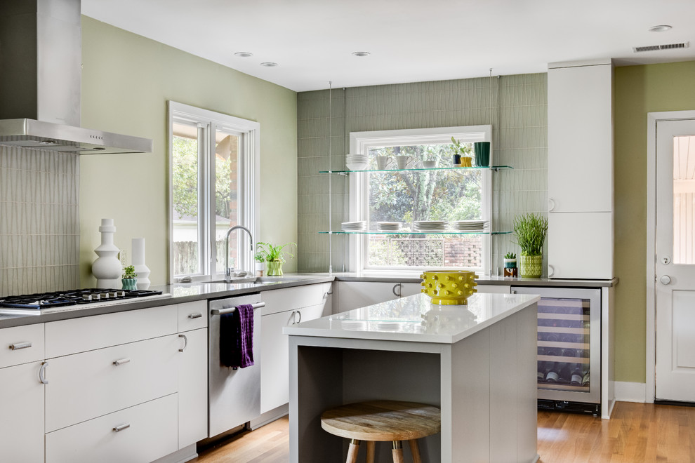 Immagine di una cucina minimalista con lavello a vasca singola, ante lisce, ante bianche, paraspruzzi grigio, elettrodomestici in acciaio inossidabile, parquet chiaro e top grigio