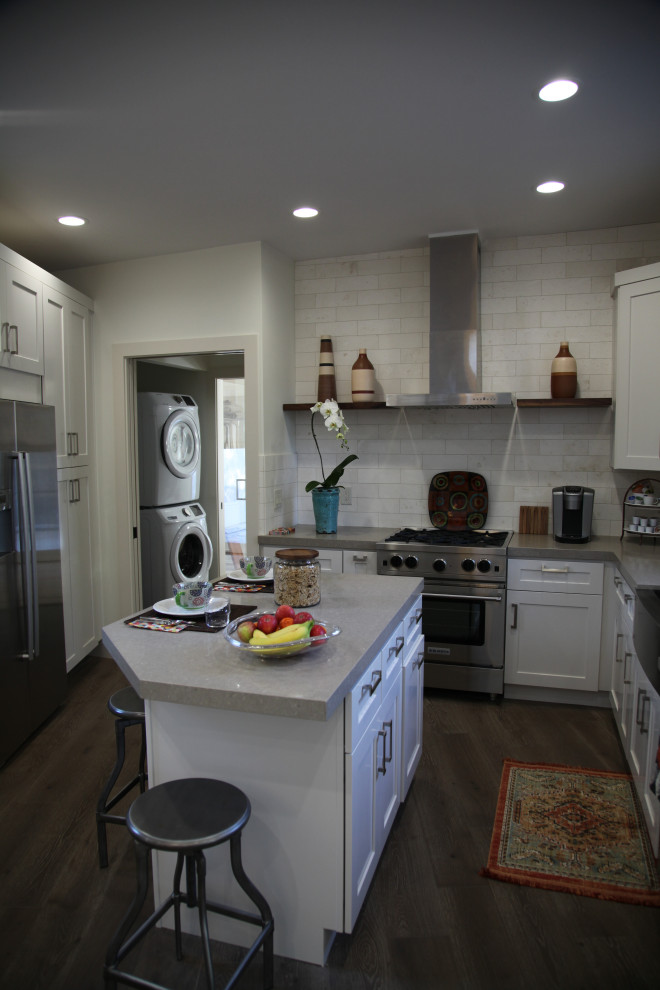 Small retro u-shaped enclosed kitchen in San Francisco with a belfast sink, shaker cabinets, white cabinets, engineered stone countertops, beige splashback, ceramic splashback, stainless steel appliances, an island, brown floors and grey worktops.