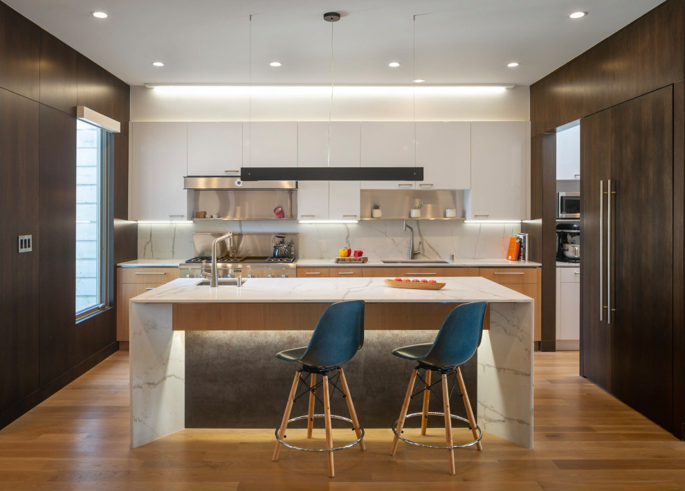 Huge 1960s u-shaped medium tone wood floor and brown floor kitchen photo in San Francisco with flat-panel cabinets, medium tone wood cabinets, quartz countertops, an island, an undermount sink, white backsplash, stone slab backsplash, stainless steel appliances and white countertops