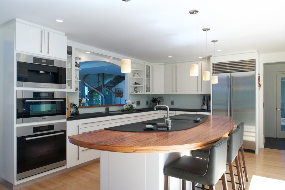 Foto di una cucina moderna di medie dimensioni con lavello sottopiano, ante lisce, ante bianche, top in legno, paraspruzzi bianco, elettrodomestici in acciaio inossidabile e parquet chiaro