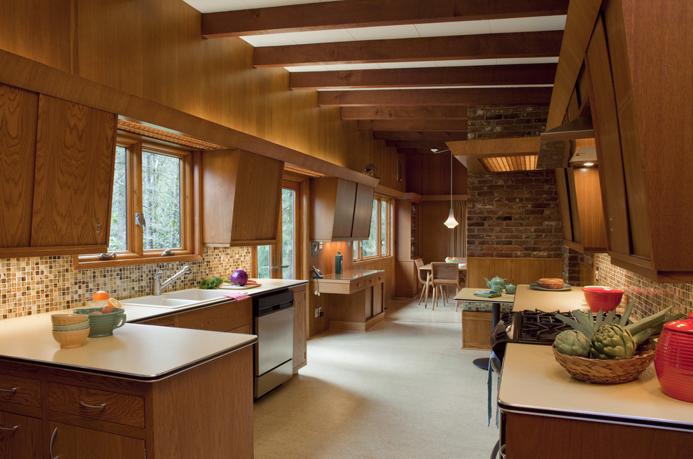 Mid-sized mid-century modern u-shaped carpeted enclosed kitchen photo in Portland with mosaic tile backsplash, a drop-in sink, flat-panel cabinets, medium tone wood cabinets, laminate countertops, multicolored backsplash, stainless steel appliances and no island