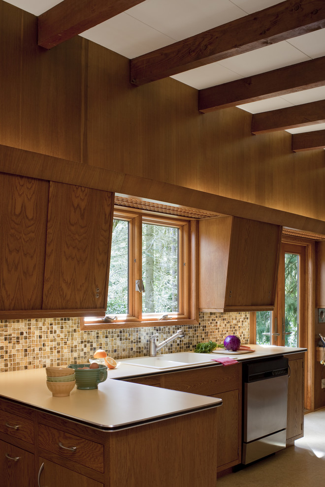 Mid-sized 1960s u-shaped carpeted enclosed kitchen photo in Portland with flat-panel cabinets, medium tone wood cabinets, laminate countertops, multicolored backsplash, stainless steel appliances and no island