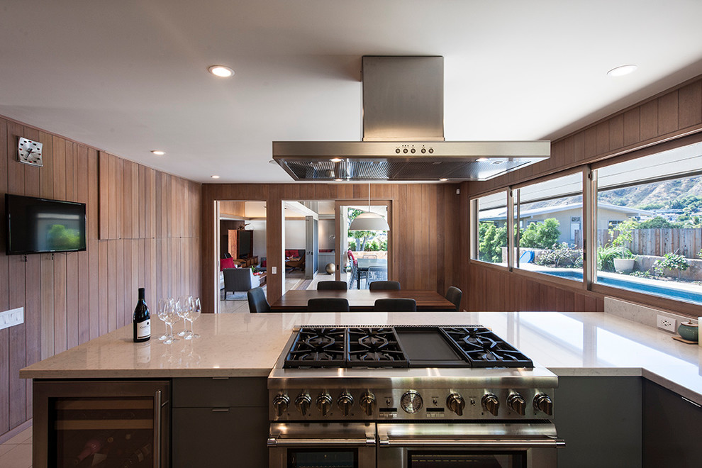 Large retro kitchen/diner in Hawaii with flat-panel cabinets, dark wood cabinets, white splashback, stainless steel appliances and porcelain flooring.