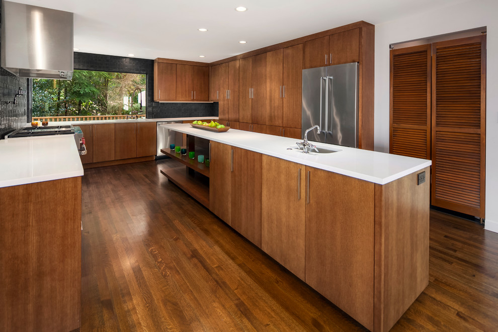 Exempel på ett stort retro kök, med en undermonterad diskho, släta luckor, bänkskiva i kvarts, svart stänkskydd, stänkskydd i cementkakel, rostfria vitvaror, mellanmörkt trägolv, en köksö, skåp i mellenmörkt trä och brunt golv