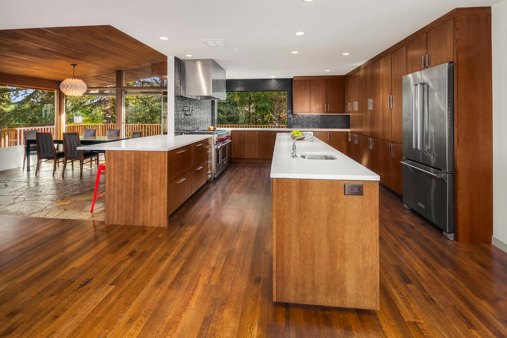 Example of a large mid-century modern u-shaped medium tone wood floor open concept kitchen design in Seattle with an undermount sink, flat-panel cabinets, light wood cabinets, quartz countertops, black backsplash, cement tile backsplash, stainless steel appliances and an island