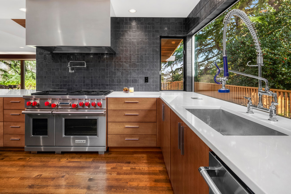 Inspiration for a large 1960s u-shaped medium tone wood floor open concept kitchen remodel in Seattle with an undermount sink, flat-panel cabinets, light wood cabinets, quartz countertops, black backsplash, cement tile backsplash, stainless steel appliances and an island