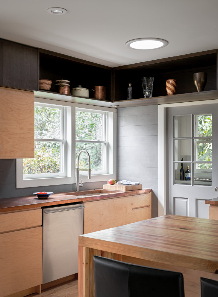 Inredning av ett retro mellanstort brun brunt kök, med en rustik diskho, släta luckor, skåp i ljust trä, bänkskiva i akrylsten, grått stänkskydd, rostfria vitvaror, ljust trägolv, en halv köksö och brunt golv
