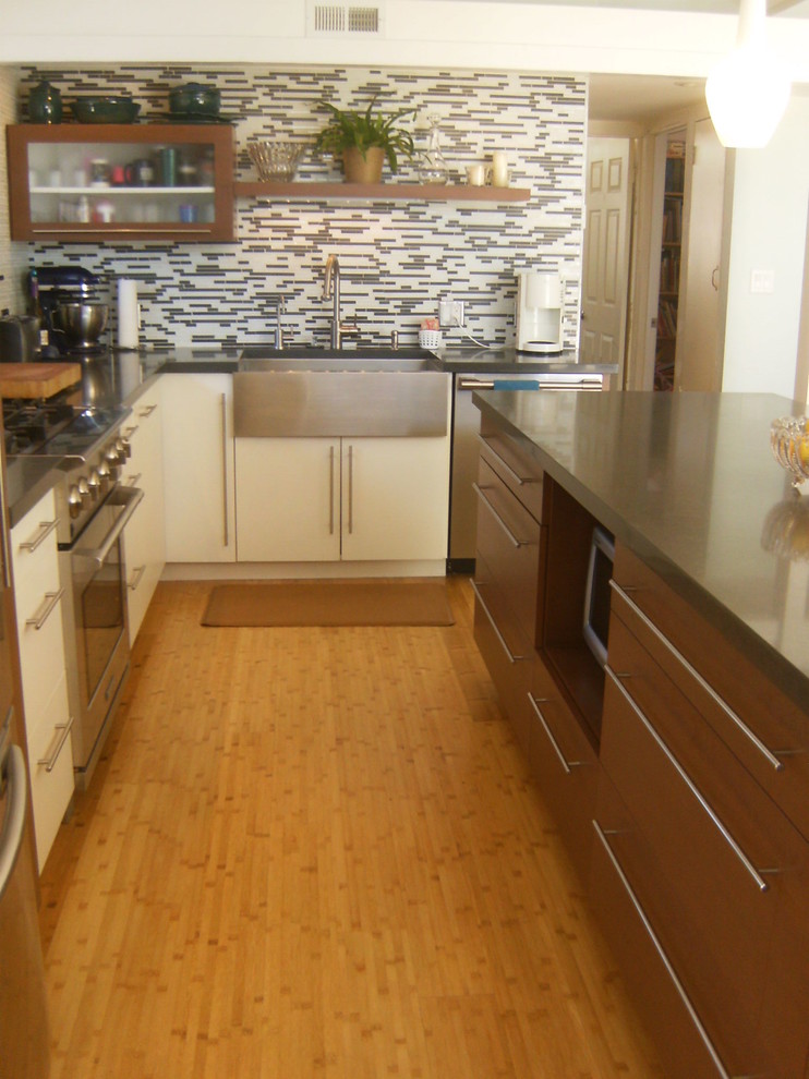 Example of a 1960s l-shaped open concept kitchen design in Los Angeles with a farmhouse sink, flat-panel cabinets, medium tone wood cabinets, quartz countertops, black backsplash and stainless steel appliances