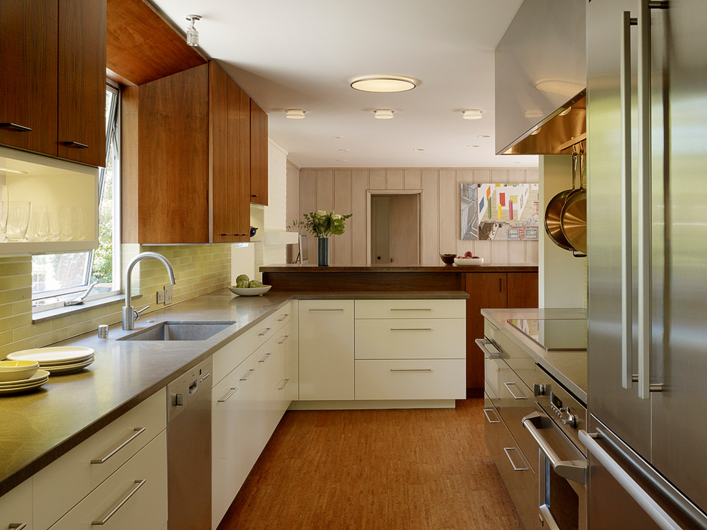 Midcentury galley open plan kitchen in San Francisco with medium hardwood flooring, a submerged sink, flat-panel cabinets, medium wood cabinets, green splashback, stainless steel appliances and brown worktops.
