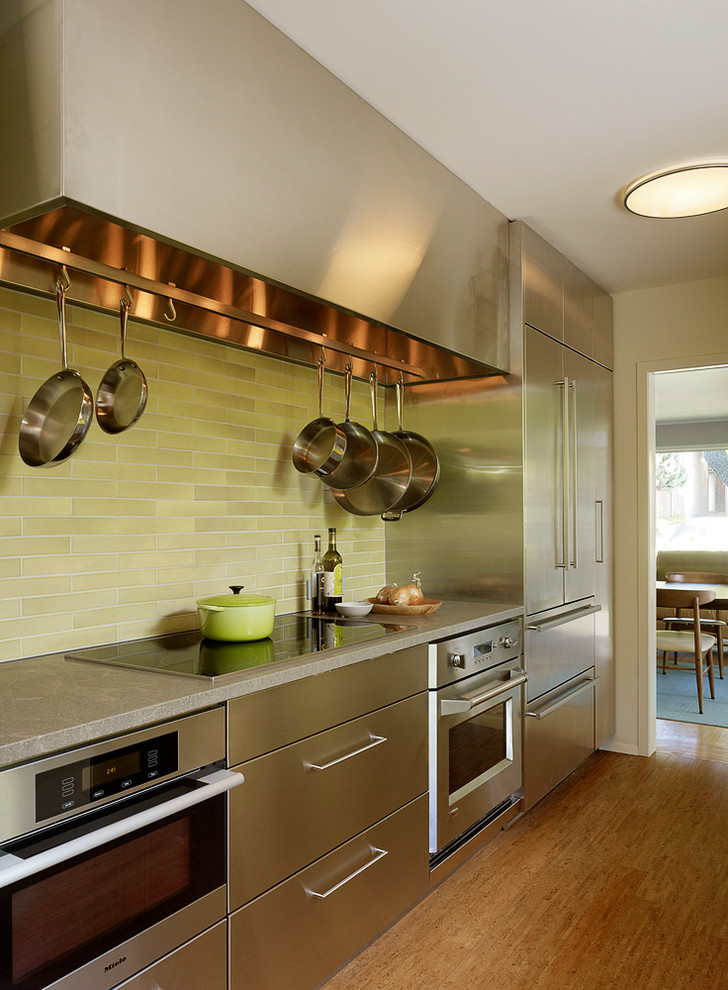 Esempio di una cucina moderna di medie dimensioni con ante lisce, paraspruzzi verde, elettrodomestici in acciaio inossidabile, nessuna isola, pavimento in legno massello medio e top grigio