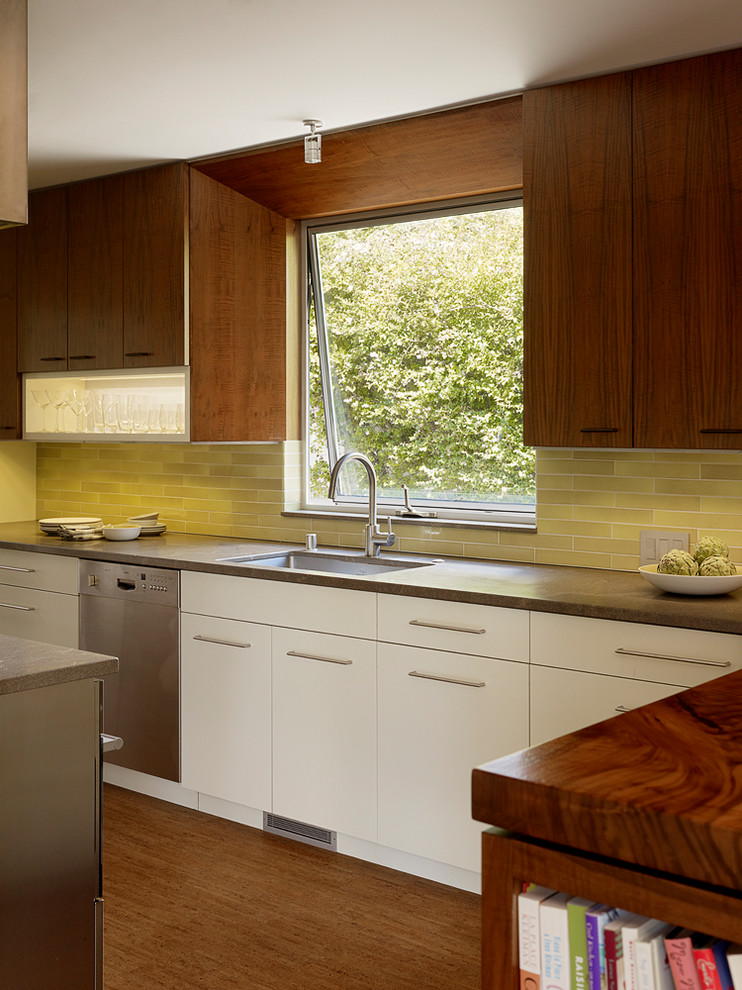 Foto på ett 50 tals brun kök, med en undermonterad diskho, släta luckor, skåp i mellenmörkt trä, grönt stänkskydd, rostfria vitvaror och mellanmörkt trägolv
