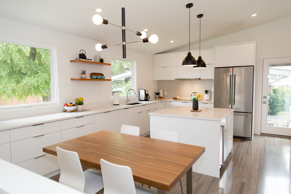 Idéer för att renovera ett stort retro vit vitt kök, med en undermonterad diskho, släta luckor, vita skåp, bänkskiva i kvartsit, grått stänkskydd, stänkskydd i keramik, integrerade vitvaror, laminatgolv, en köksö och grått golv