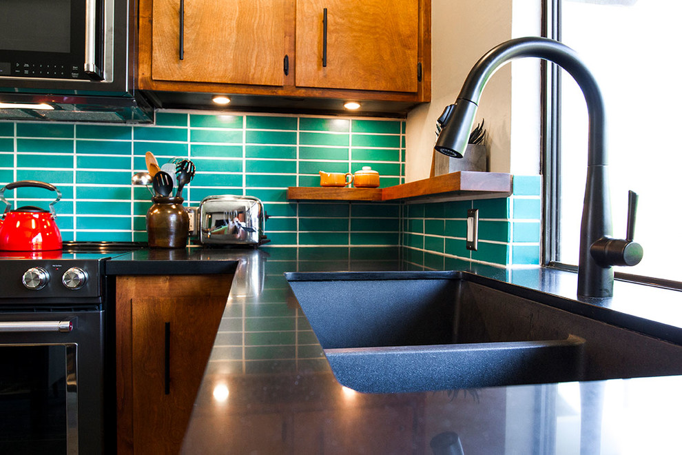Foto på ett 50 tals kök, med skåp i mörkt trä, grönt stänkskydd, stänkskydd i keramik och en köksö