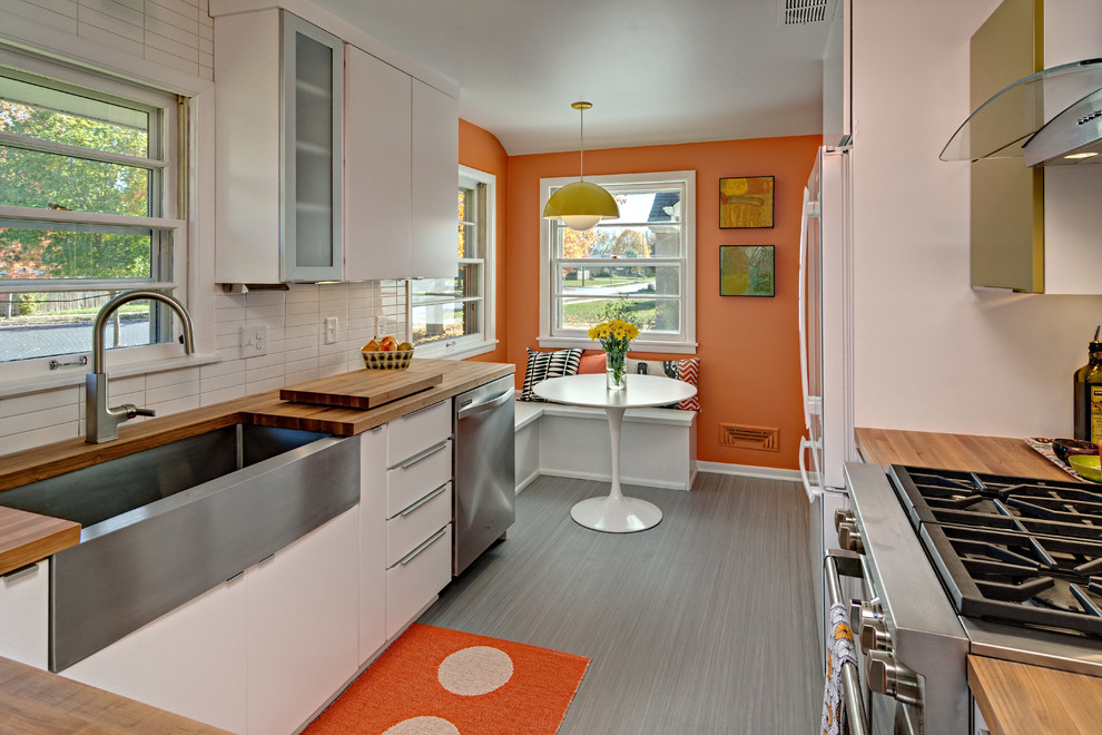 Mid-century modern kitchen photo in Minneapolis with a farmhouse sink, flat-panel cabinets, white cabinets, wood countertops, white backsplash and stainless steel appliances