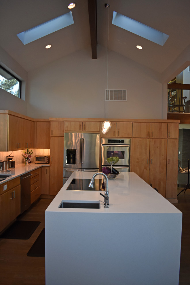 Esempio di una cucina design con ante lisce, ante in legno chiaro, elettrodomestici in acciaio inossidabile, lavello sottopiano, paraspruzzi bianco, pavimento in legno massello medio e pavimento marrone