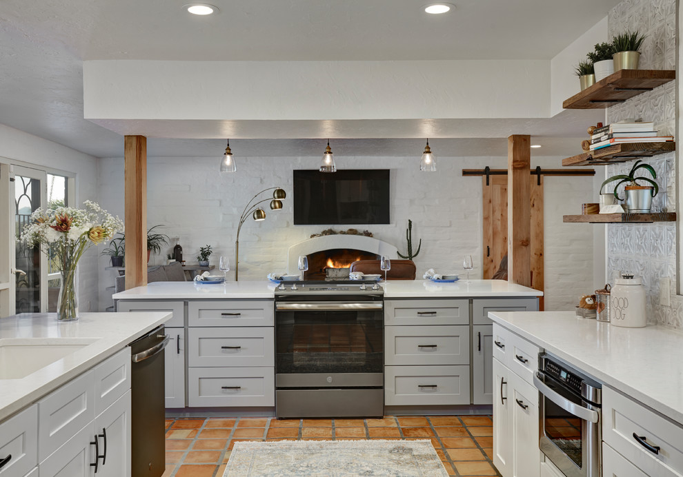 Idéer för att renovera ett mellanstort 60 tals vit vitt kök, med en undermonterad diskho, skåp i shakerstil, vita skåp, bänkskiva i kvartsit, flerfärgad stänkskydd, stänkskydd i metallkakel, rostfria vitvaror, klinkergolv i terrakotta, en köksö och rött golv