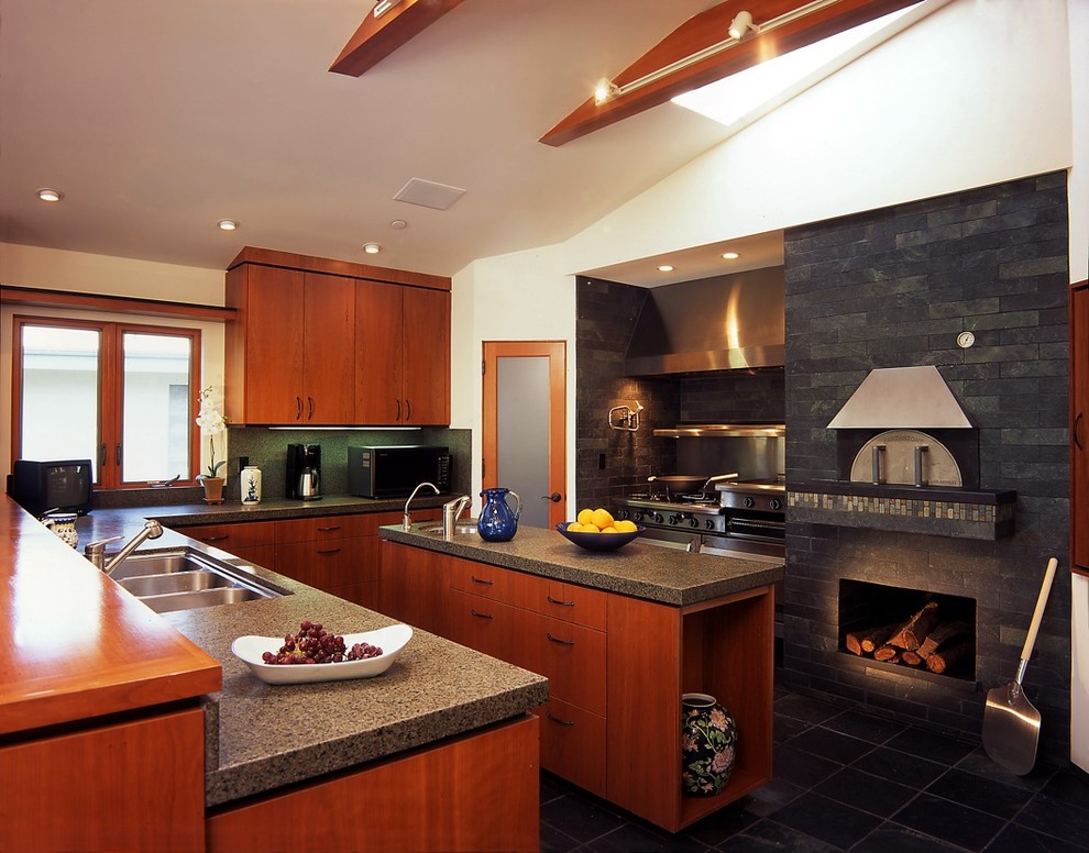 Imagen de cocina retro con encimera de granito, electrodomésticos de acero inoxidable y pared de piedra