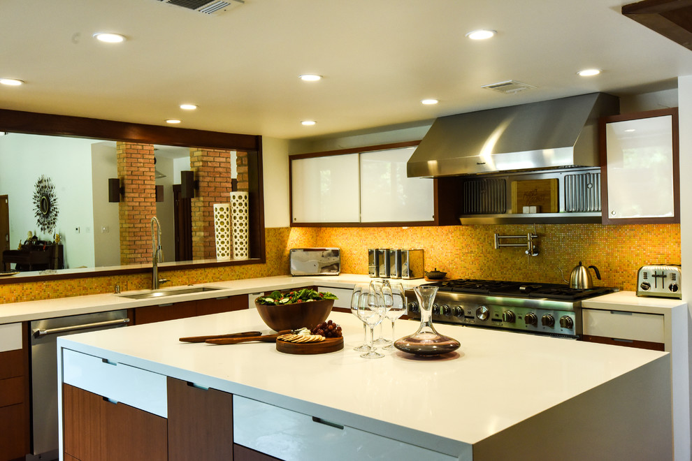 Example of a 1960s u-shaped eat-in kitchen design in Houston with an undermount sink, flat-panel cabinets, medium tone wood cabinets, solid surface countertops, orange backsplash, mosaic tile backsplash, stainless steel appliances and an island