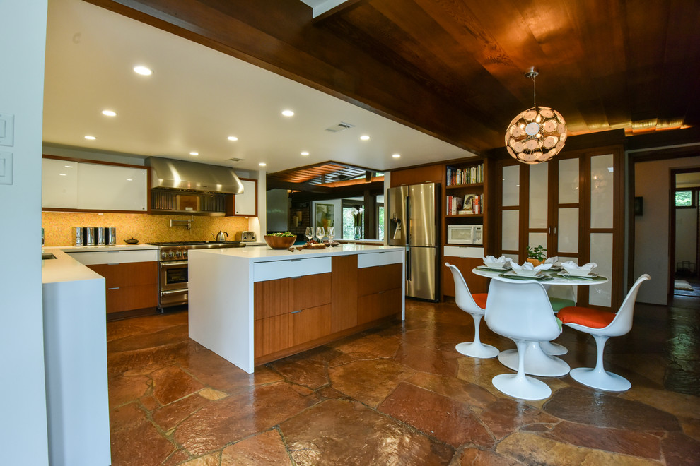 Inspiration for a mid-century modern u-shaped eat-in kitchen remodel in Houston with an undermount sink, flat-panel cabinets, medium tone wood cabinets, solid surface countertops, orange backsplash, mosaic tile backsplash, stainless steel appliances and an island