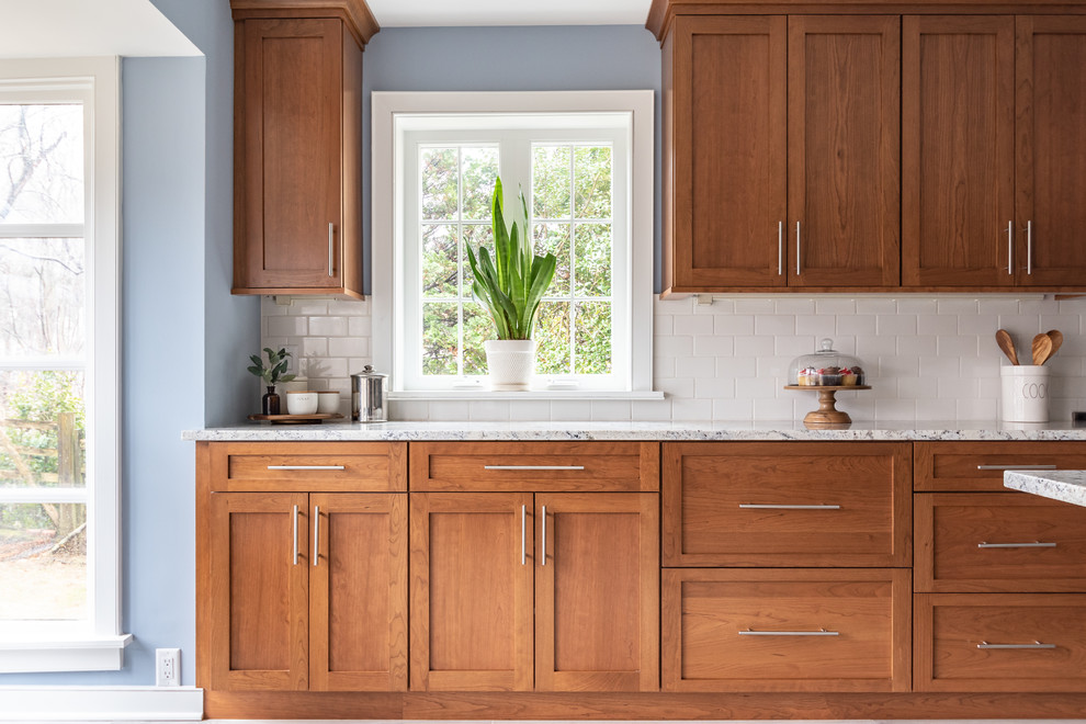 Foto på ett mellanstort retro flerfärgad kök och matrum, med en undermonterad diskho, luckor med infälld panel, bruna skåp, bänkskiva i kvartsit, vitt stänkskydd, stänkskydd i porslinskakel, rostfria vitvaror, klinkergolv i porslin, en köksö och grått golv